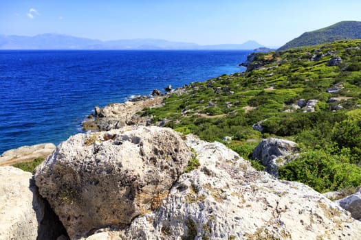 The beautiful seascape of the Ionian Sea opens with large stone boulders.