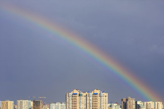 Bright rainbow in the sky above urban houses after a thunderstorm.