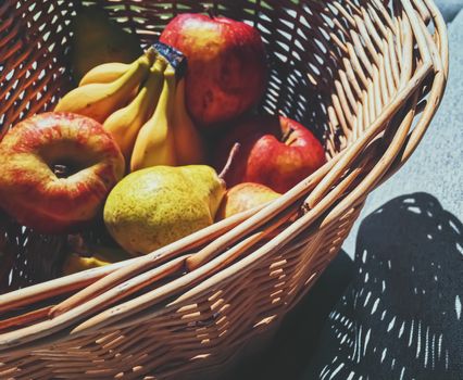 Organic apples, pears and bananas on rustic in a wicker basket, fruits farming and agriculture
