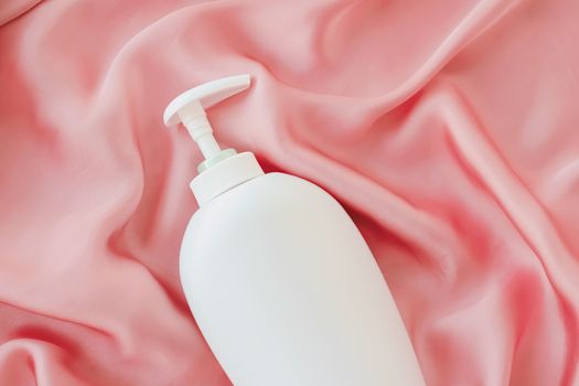 Blank label cosmetic container bottle as product mockup on pink silk background, hygiene and healthcare