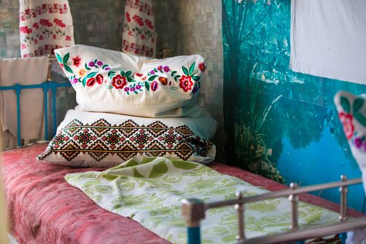 An ancient iron bed with embroidered cushions.Old Iron Bed with pillows.Embroidered pillows on an old bed