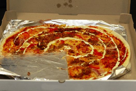 Pizza in a box with a broken piece. Pizza from the cafe. Pizza. The usual standard pizza.