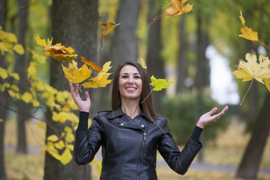 A woman is throwing autumn leaves