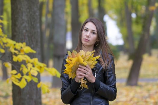 Girl with a bouquet of autumn leaves