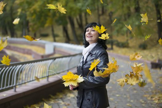 Mature woman in autumn leaves