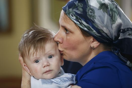 Belarus, the city of Gomel, St. Nicholas Monastery.June 11, 2016.Baptism of the Child.A mother kisses a baby.Mother pities her son. Infant and mother