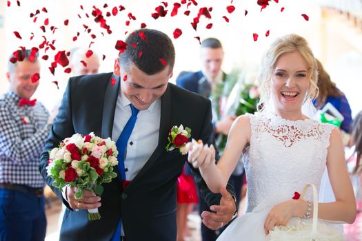 on the bride and groom throw rose petals. Bride and groom happy in rose petals