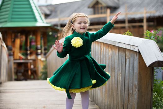 Russia, Moscow, Izmaylovsky Park, August 27, 2017. International Photo Festival.A joyful little girl runs along the path. Beautiful little girl in a green coat