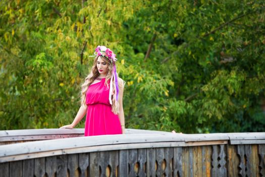 Russia, Moscow, Izmaylovsky Park, August 27, 2017. International Photo Festival.A girl with a wreath on her head is walking on the bridge. A girl with a wreath on her head in an ethnic manner.