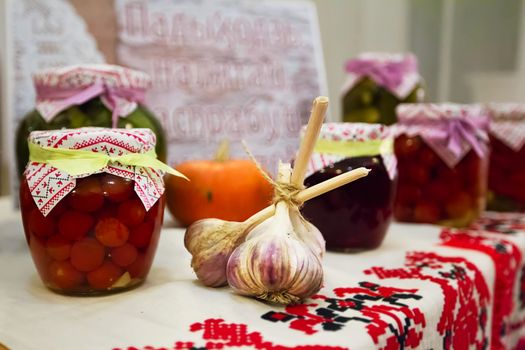 Preservation of vegetables. Canned tomatoes. Head of garlic. Belarusian products on the Belarusian towel. National Belarusian cuisine