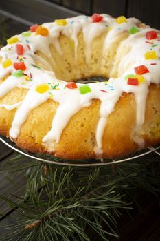Fresh baked yeast cake or brioche with icing on dark wooden table, vertical image