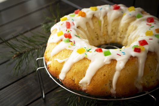 Brioche dough or babka on dark wooden table with icing and colorful decoration