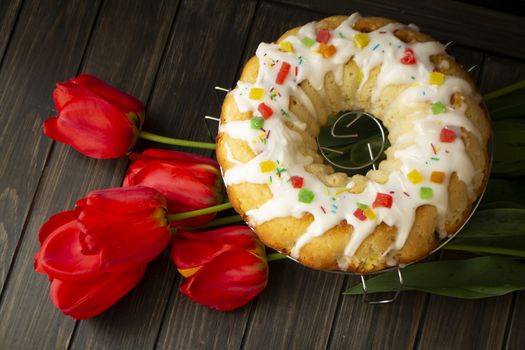 walnut brioche roll or babka on dark wooden background with red tulips