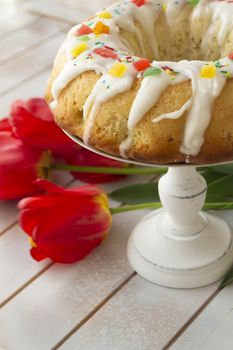 Easter babka cake and bright tulips on a vintage table. Easter family breakfast. Vertical image