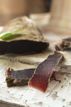 Sliced venison steak, dry meat of wild roe on rustic wooden board, vertical image