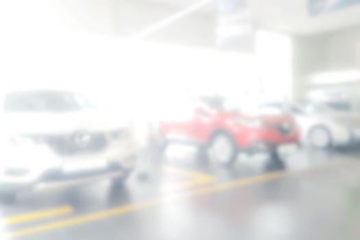 Blurred background of dealership with new cars for sale in the row