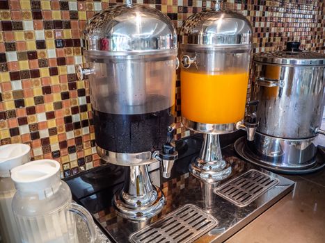 Fruit juice dispensers and coffee & tea water on a self service breakfast counter in a hotel.