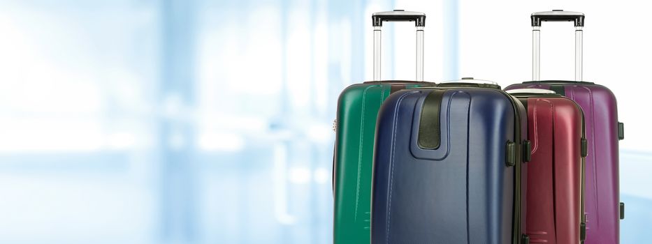 Travel concep banner - group of various travel suitcases on a blurred background of the airport (copy space)