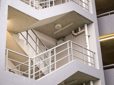 walking on the stair on the side of a white multi storey parking lots building