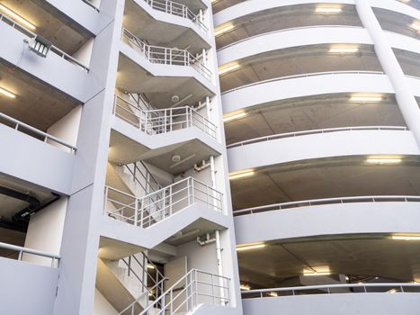 walking on the stair on the side of a white multi storey parking lots building