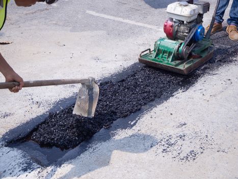 Worker use vibratory plate compactor compacting asphalt at road repair