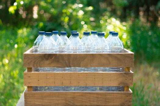 Reuse of the concept of recycling plastic bottles. Plastic bottles with stoppers in a recycled wooden box with beautiful sunset in the garden