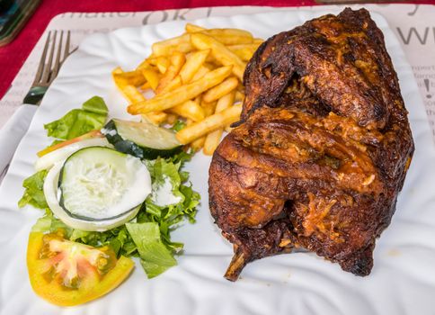 Half chicken fries salad on a plate in the town of Bijilo in The Gambia, West Africa