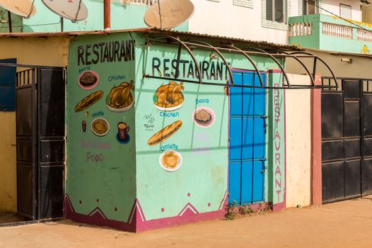 BIJILO, GAMBIA-January 06, 2020: Mural on a facade representing the dishes sold in a restaurant on a road from Bijilo in The Gambia, West Africa