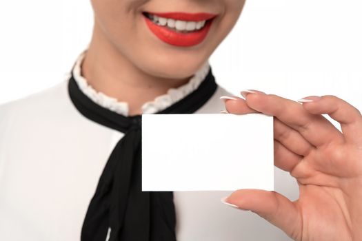 Young business woman with perfect smile and fingernails holds blank business card in close-up on a white background.