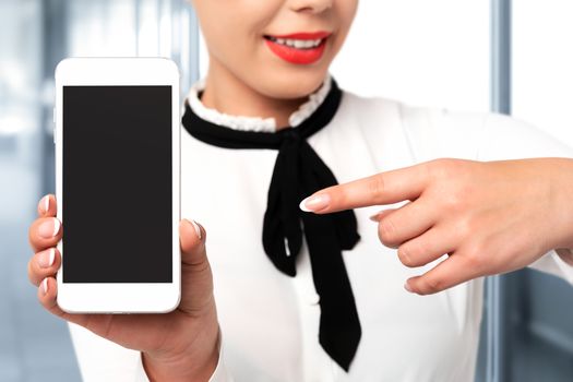 Mobile technology advertising concept image - elegant woman in formal business clothing with perfect fingernails holding smartphone with blank screen.