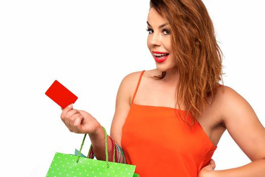 Beautiful woman in an orange dress holds a blank gift card in her hand and enjoys the shopping