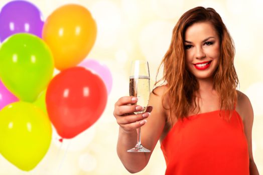 Celebration event concept - young and attractive woman in a red dress with perfect fingernails holds a glass of champagne or wine and smiling on a party decoration background (mixed).