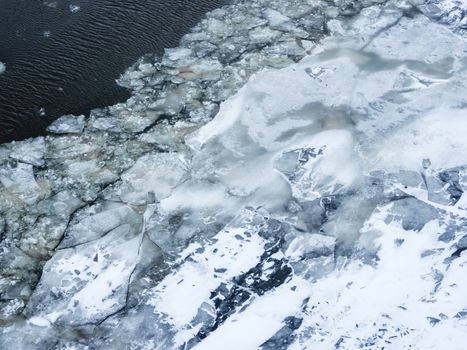 Broken ice on a frozen river. Water with shards of ice.