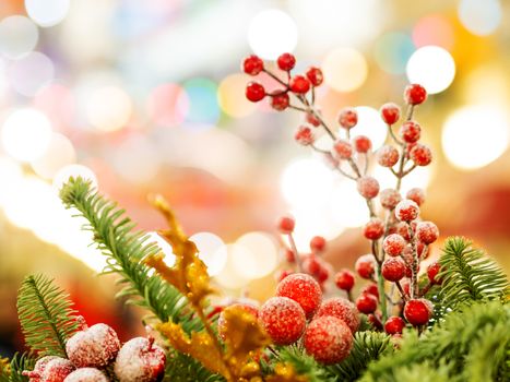 Christmas and New Year background with fir tree wreath and berries. Shiny golden decorations and light bulb bokeh.