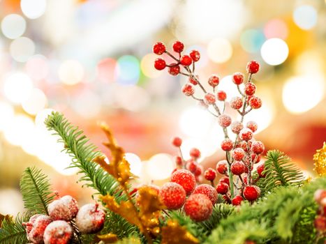 Christmas and New Year background with fir tree wreath and berries. Shiny golden decorations and light bulb bokeh.