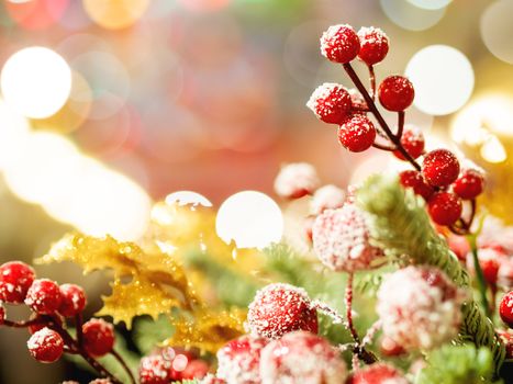 Christmas and New Year background with fir tree wreath and berries. Shiny golden decorations and light bulb bokeh.