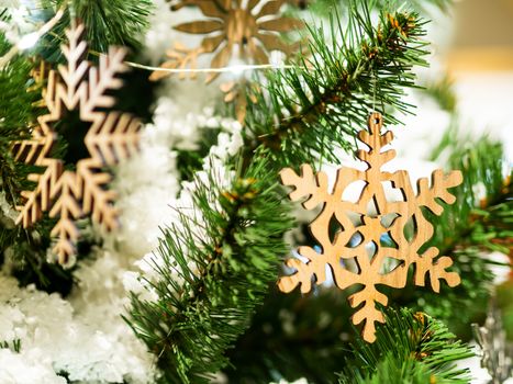 Christmas and New Year rustic decorations - wooden snowflakes on Christmas tree with light bulbs.