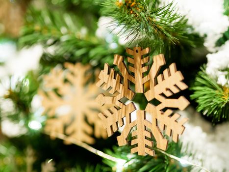 Christmas and New Year rustic decorations - wooden snowflakes on Christmas tree with light bulbs.