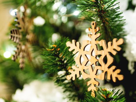 Christmas and New Year rustic decorations - wooden snowflakes on Christmas tree with light bulbs.