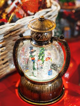 Three snowmen inside vintage snow globe with spangles. Christmas retro toy.