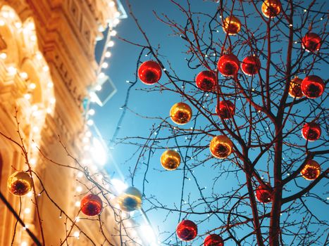 Streets of Moscow decorated for New Year and Christmas celebration. Tree with bright red and yellow balls. GUM (Main Department Store) building with light bulbs. Russia.