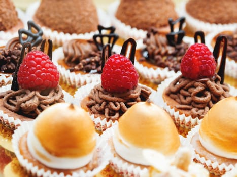 Tasty pastry with fresh raspberries. Different little tarts with chocolate topping, whipped cream and edible decorations.