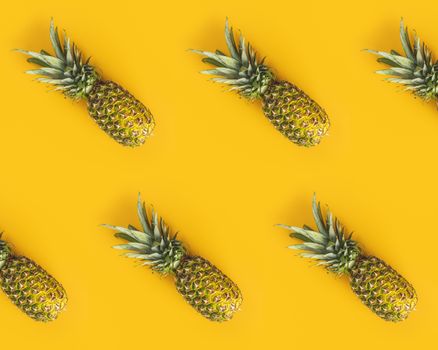 Fresh ripe pineapples on yellow background. Summer concept. Creative flat lay with copy space. Top view.