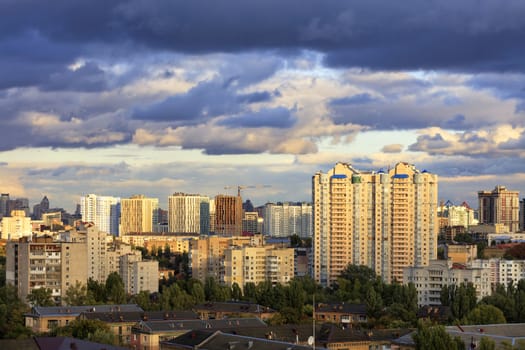 The beautiful light of the setting sun breaks through the heavy autumn clouds and falls on the houses in the city landscape.