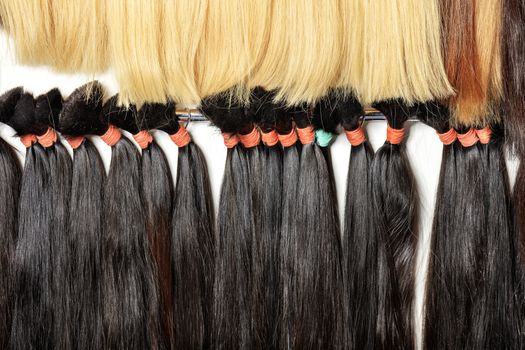 Haircare female hair, technology, style and beauty concept. Natural black and white, brown, shiny, colored shiny healthy human hair bundles for extension and weave wigs making.