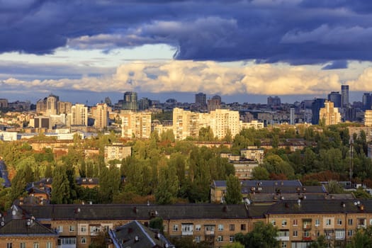 The beautiful light of the setting sun breaks through the heavy autumn clouds and falls on the houses in the city landscape.