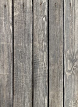 Weathered old gray wooden fence nailed with rusty nails. Vertical layout.