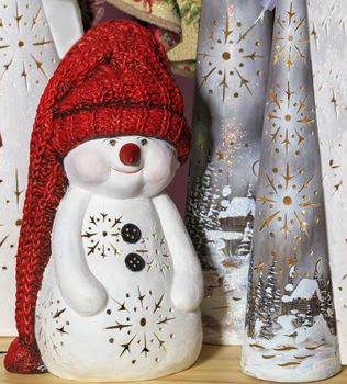 Decorative toy snowman in a long red knitted hat, on New Year's Eve against the background of New Year's Christmas caps.