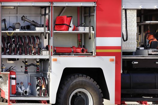 Fire hoses, valves, cranes, road cones, hydrants and manual fire extinguishers are located in the cargo compartment of an equipped fire truck, free copy space.