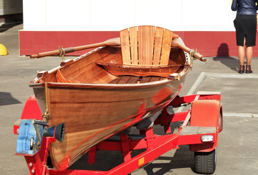 Beautiful wooden orange canoe parked by a young businesswoman in front of an office building in a car park, copy space image.